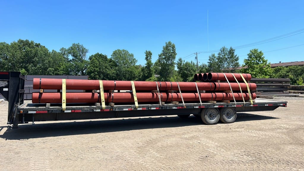 Industrial pipe bundle strapped on Red Shark Transport flatbed trailer